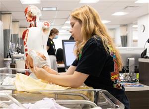 Nursing camp student changing a baby
